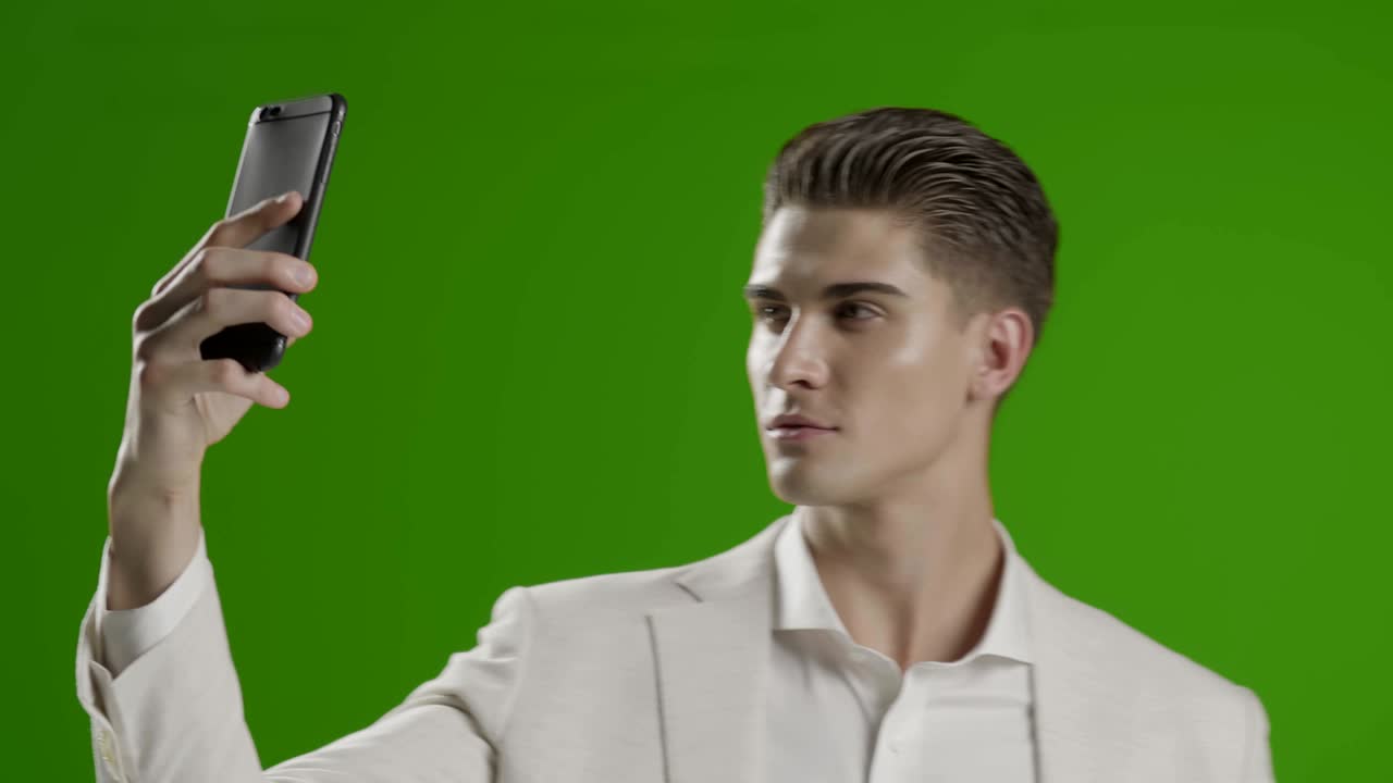 잘생긴 젊은 사업가 스마트폰을 사용하는 녹색 화면 웃으며 전화로 사진 셀피를 찍습니다.