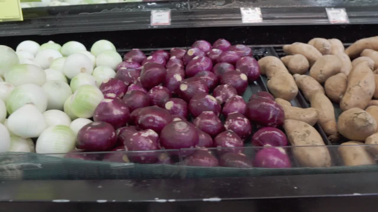 Fresh potatoes and onions displayed at a grocery store produce section