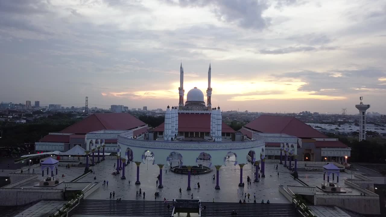 Reversal drone shot of the great Mosque of Central Java (MAJT) in suset time. Th sun is orange and the weather is cloudy