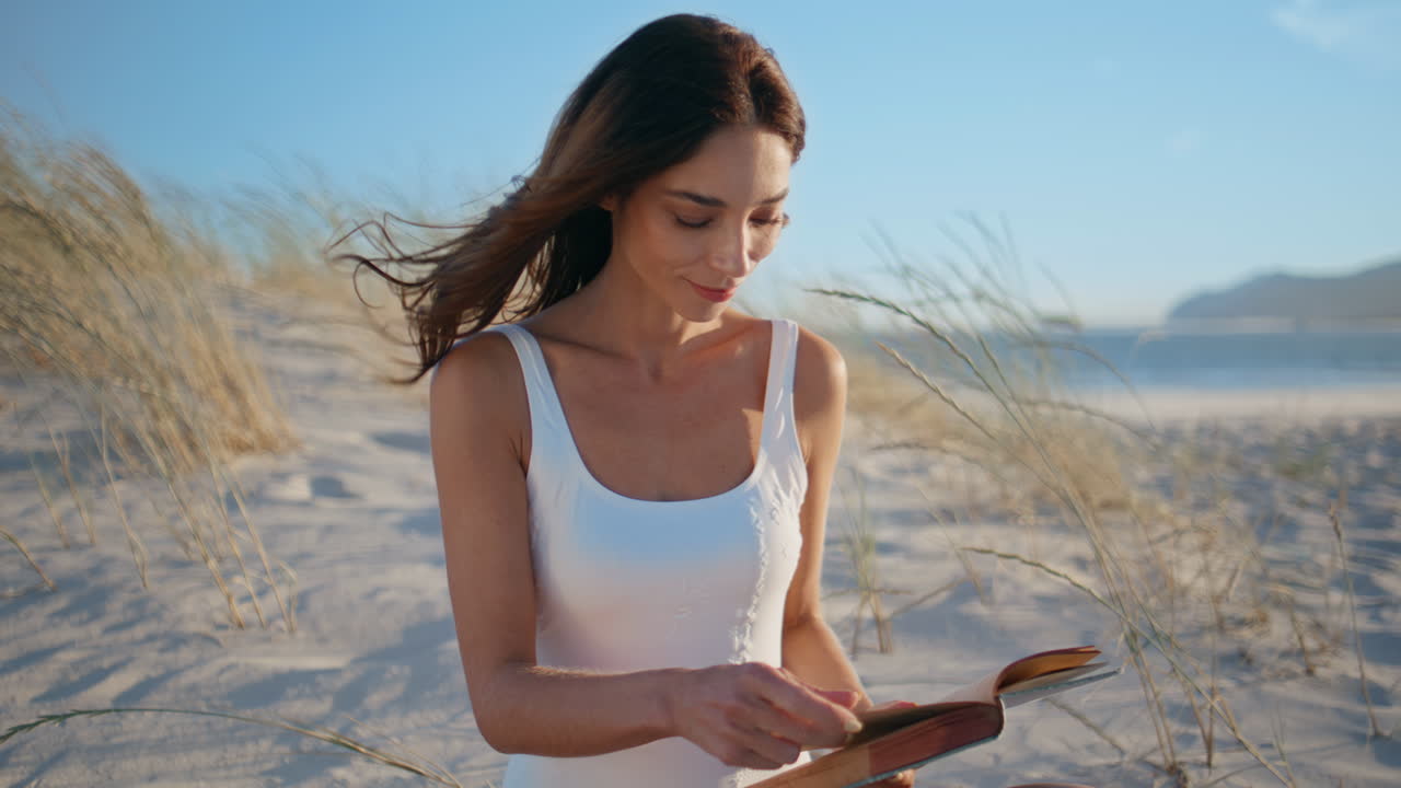 Calm girl reading book on windy shoreline closeup. Smiling woman flipping pages