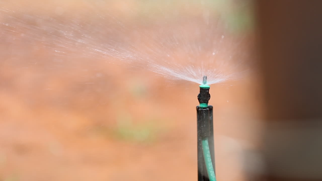 Primo piano di una testina dell'irrigatore che spruzza acqua, che sfoca lentamente dietro un oggetto
