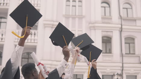 multicultural group of graduate students flapping their caps on air