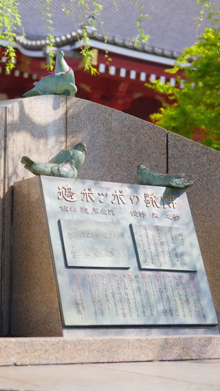 Stone sculpture at the Senso-ji temple in daylight in Tokyo, Japan. Vertical. Translation: "The title and lyrics of the The Pigeon Song"