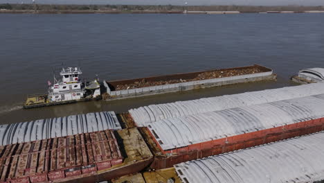 aerial footage focused on a tug boat that is pushing against a barge full of scrap metal in baton rouge, louisiana