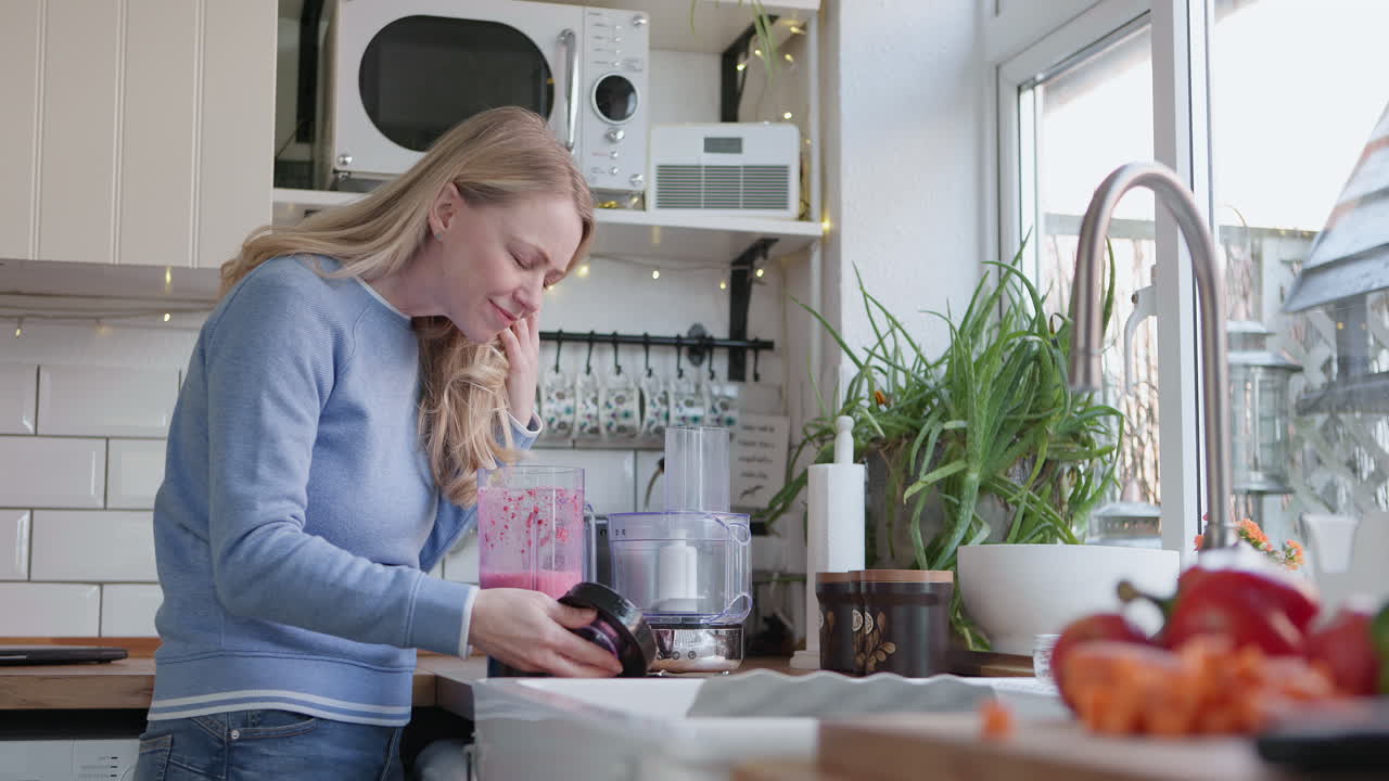Woman making smoothie in kitchen
