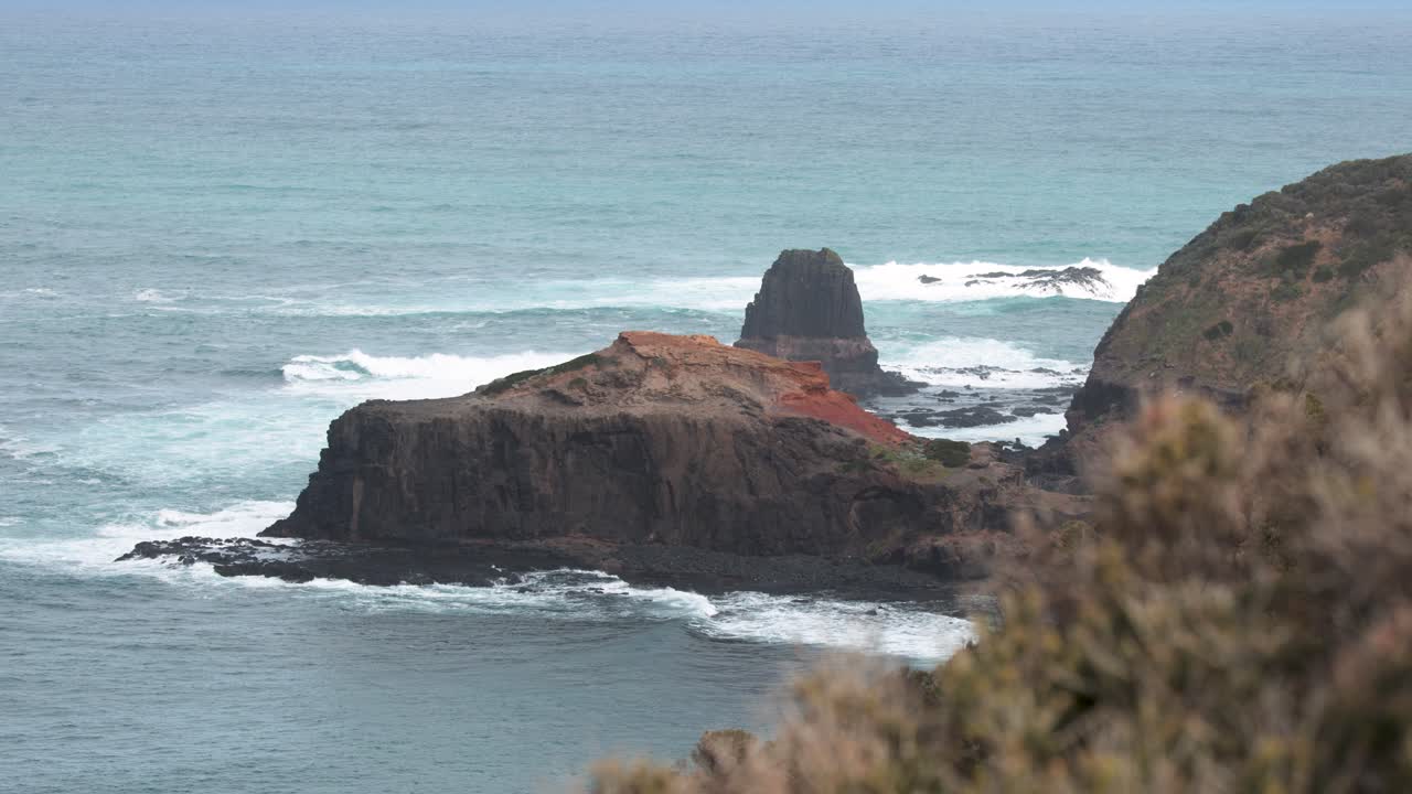 Wide shot of rugged coastal cliffs, ocean waves, and overcast natural lighting, minimal camera movement
