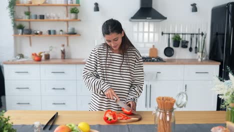 mujer cortando pimienta roja en una cocina moderna