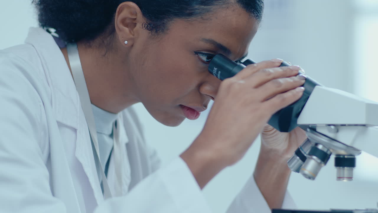 African-American Female Scientist Doing Lab Test with Microscope