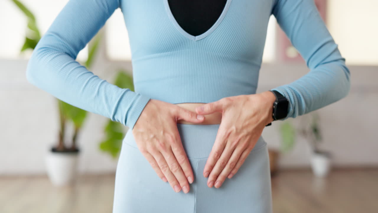 Woman making heart shape with hands on abdomen