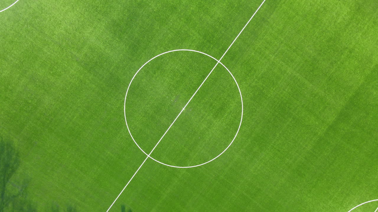 Pemandangan udara dari atas ke bawah dari titik tengah lapangan sepak bola - drone naik ke atas dan berputar