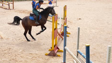Female rider clears a hurdle during training as coaches film in the background for later review