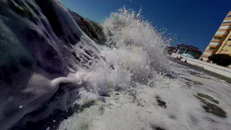 a close up shot of sea waves splashing towards the beach and forming white foam