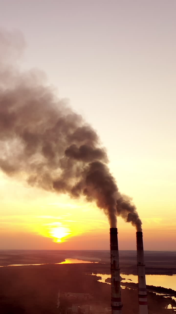 Industrial landscape. Smoke from pipes of the power plant at sunset. Environmental pollution. Vertical video