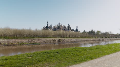 majestic view of chambord castle with canal and trees under clear blue sky