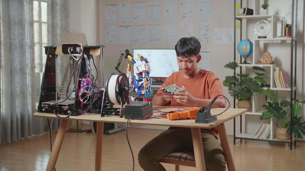 집에서 사이보그 손을 수리하는 동안 회로판을 들고 있는 아시아 소년