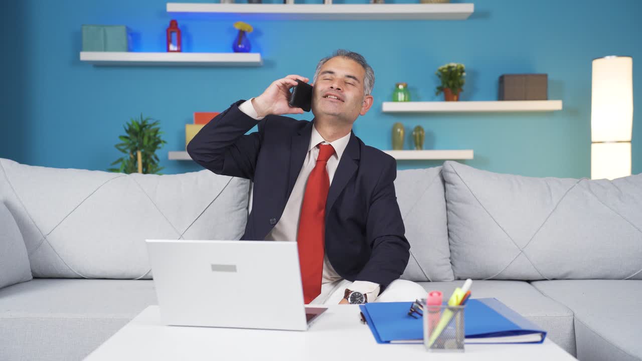 가정 사무실 노동자 남자가 행복하게 전화로 이야기하고 있습니다.