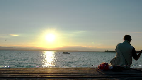 viejo pescador italiano tratando de pescar a la luz de la mañana, lago de garda en italia