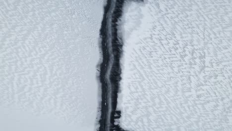 Frozen-winter-lake-in-Poland,-icy-desert-with-snow-pattern,-aerial-rise-up