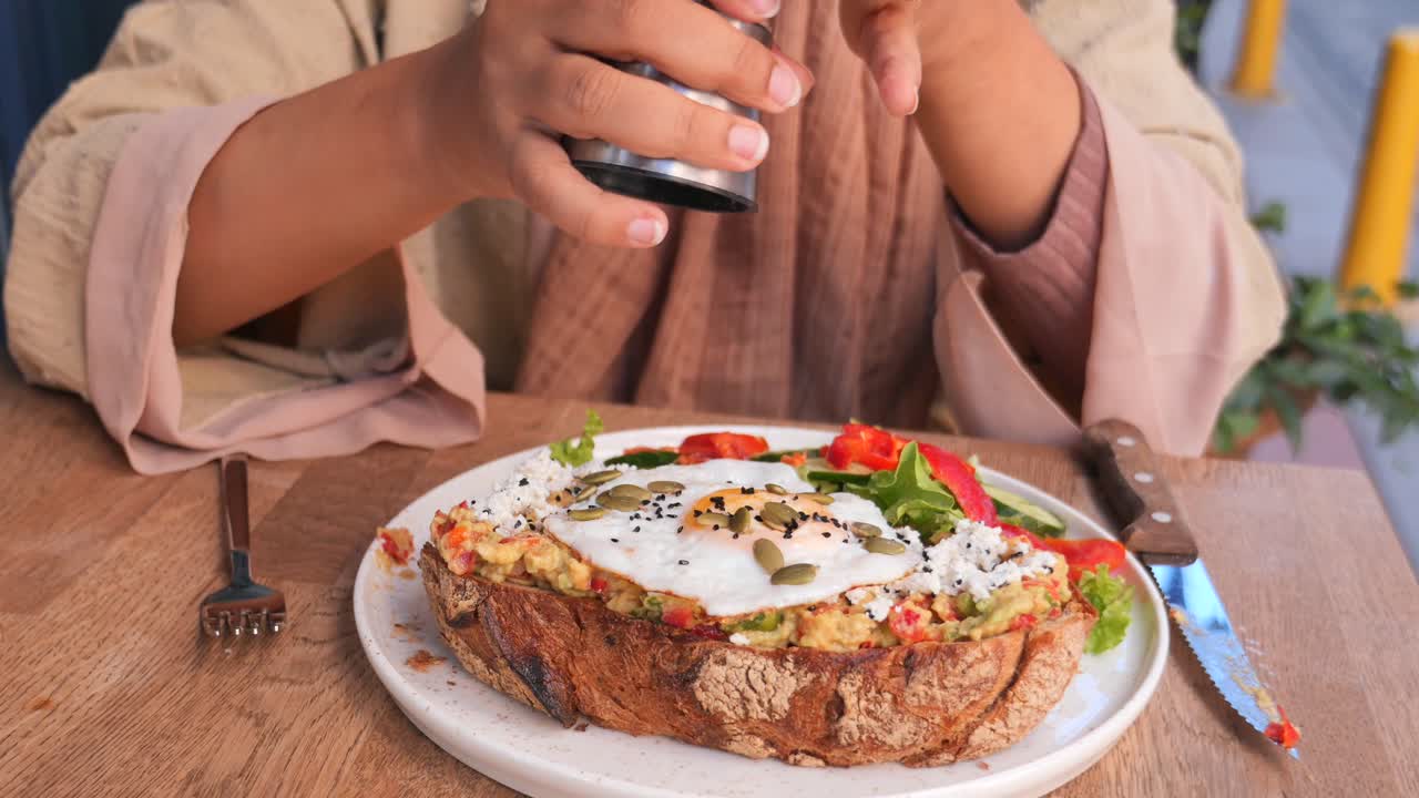 mujer comiendo tostadas de aguacate con huevo en una cafetería