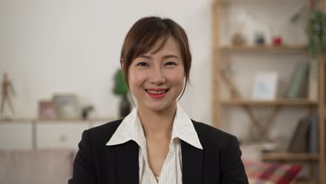 half length portrait of a professional pretty asian female insurance agent wearing suit and looking at camera. she smiles while posing at client’s home background