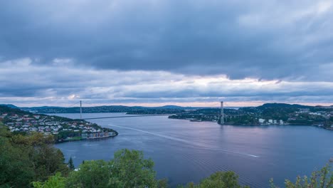 view from lyderhorn towards the askoy bridge as daylight fades behind heavy clouds streaking across the sky in time lapse