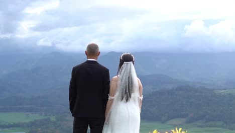 a man and a woman in love , looking at a scenic view of cloudy mountains, hand in hand