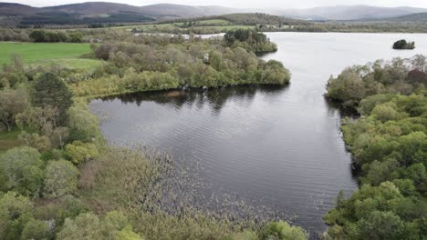 Imágenes-Aéreas-De-Drones-Que-Vuelan-Sobre-Campos-Y-árboles-Para-Revelar-Un-Lago-De-Agua-Dulce-Y-Un-Paisaje-Boscoso-Montañoso-Con-Lluvia-En-La-Distancia