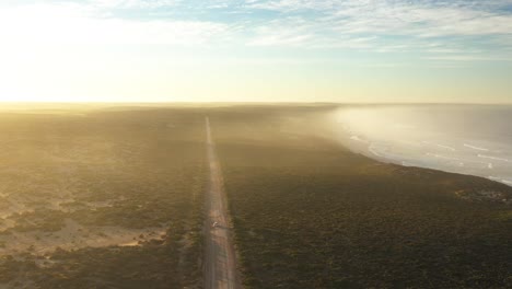 Excelente-Toma-Aérea-De-Un-Coche-Conduciendo-Por-Una-Carretera-Solitaria-Junto-A-La-Bahía-Rayada-En-La-Península-De-Eyre,-Sur-De-Australia