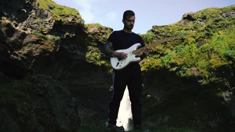 man playing guitar in front of a beautiful waterfall in iceland