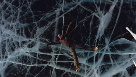 un hombre yace en el hielo en invierno, balanceando sus brazos y piernas hacia un lado, fingiendo que está nadando en el agua.