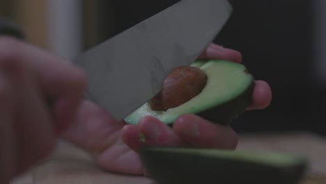 quitando el hoyo de aguacate con un cuchillo de cocina, un primer plano de cámara lenta en las manos