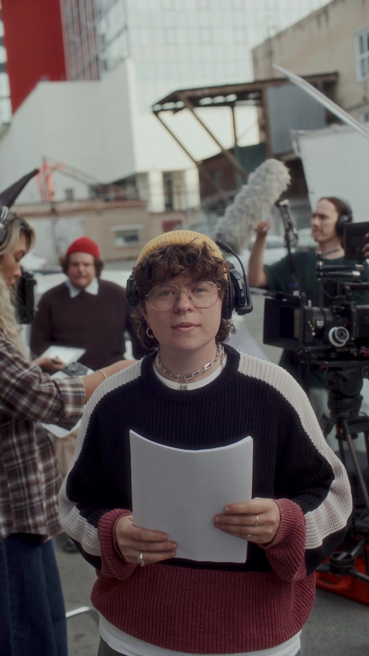 Ritratto di giovane segretaria di edizione che tiene in mano dei fogli su un set cinematografico all'aperto.