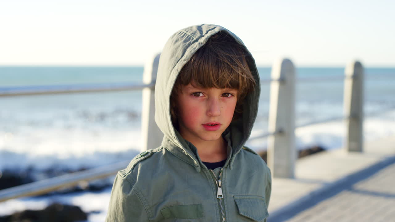 Sad, cold and face of a child at the beach