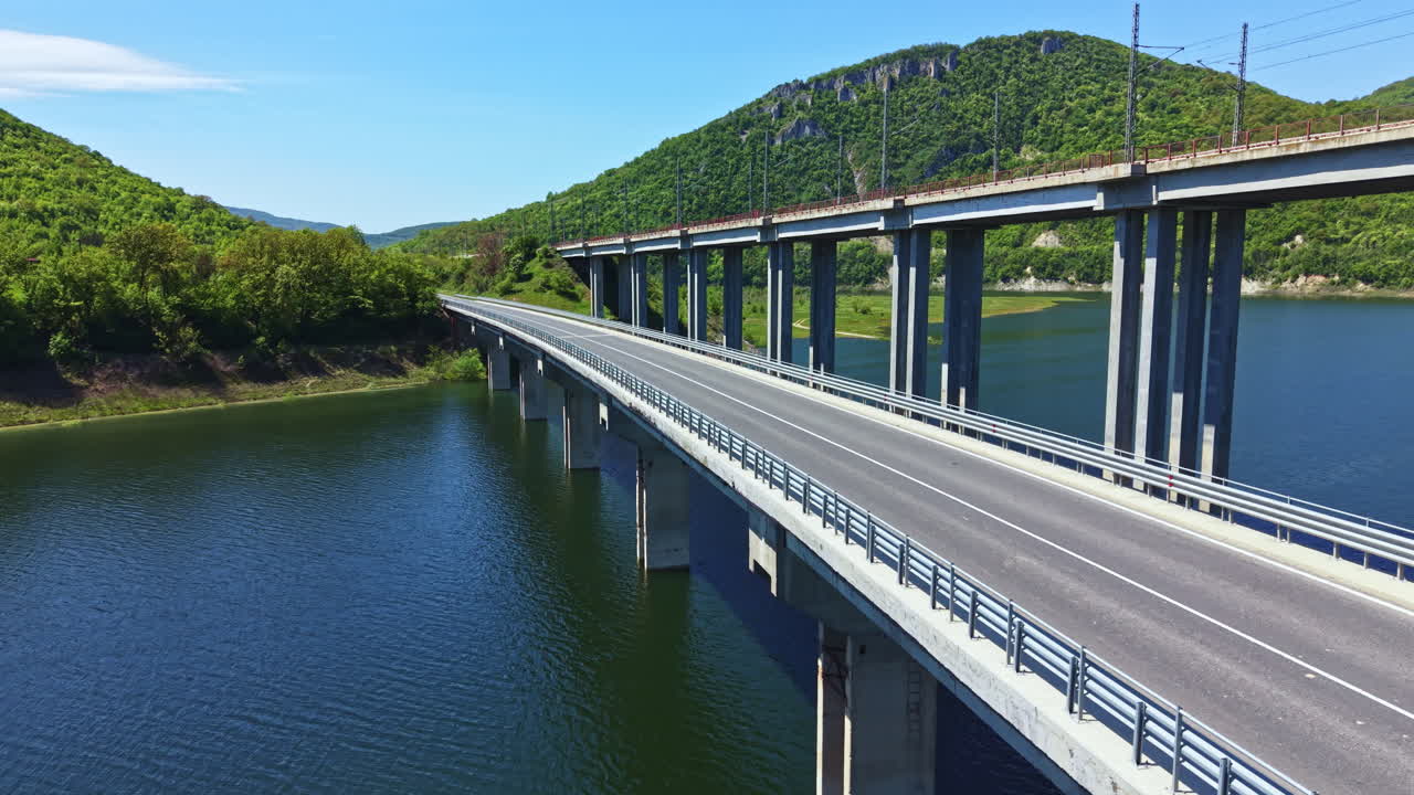 Un ponte si estende sull'acqua vicino alle montagne in una giornata limpida e soleggiata in una zona rurale senza persone.