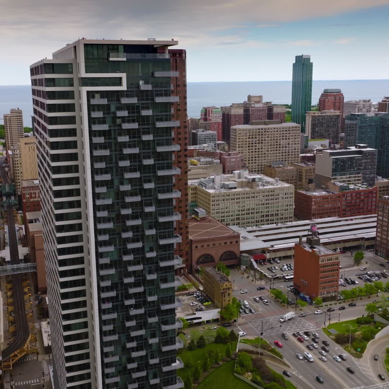 Lively traffic road among the beautiful architecture of Chicago. Railway of subway between the buildings. Drone descending footage