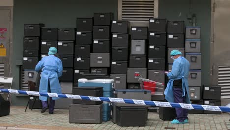 health officials wearing personal protective equipment clean food containers outside a building placed under lockdown after a large number of residents tested covid-19 coronavirus positive