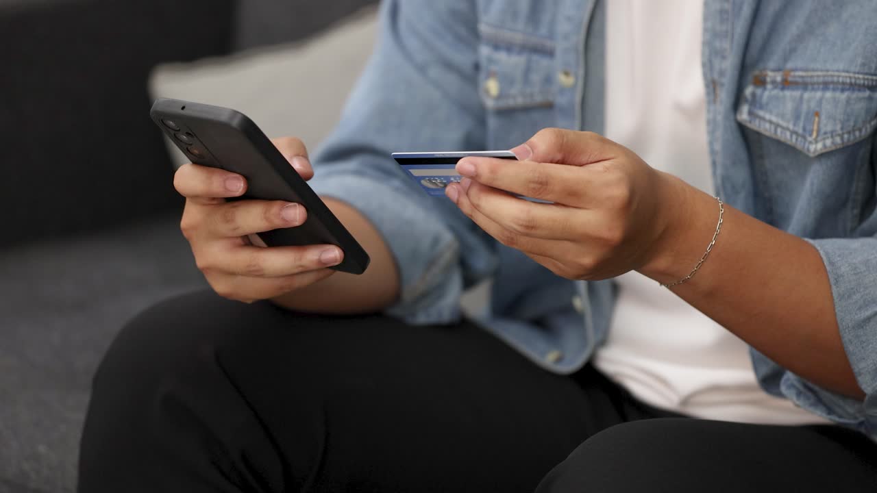 Primo piano di mani che digitano su uno smartphone mentre tengono una carta di credito per transazioni online