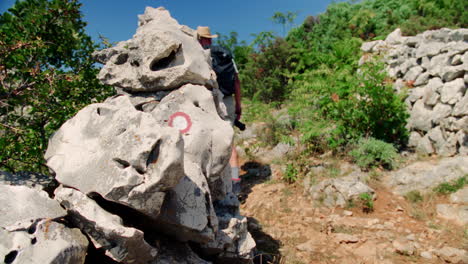 un hombre camina entre paredes de roca a lo largo de un sendero de senderismo con una cámara mientras explora la belleza natural de croacia