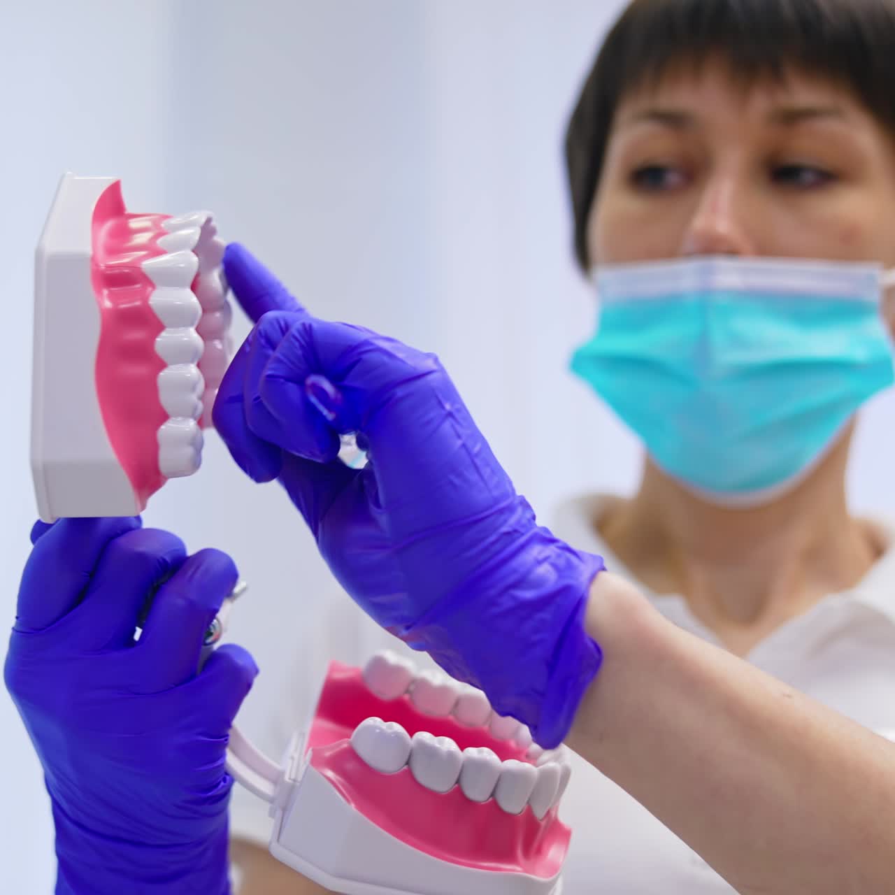 Jaw model in dentist's hands. Professional female stomatologist teaching teeth care treatment on a jaw mock in clinic. Close-up