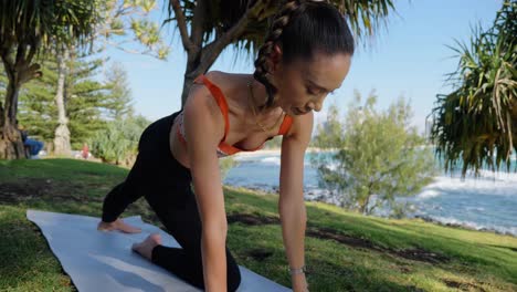 yogi doing side plank on the knee with arm extended - burleigh hill near burleigh heads beach in gold coast, qld, australia