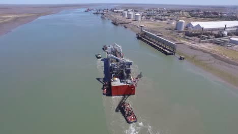 Aerial-view-of-cargo-ship-arriving-at-the-port-with-the-help-of-tugs