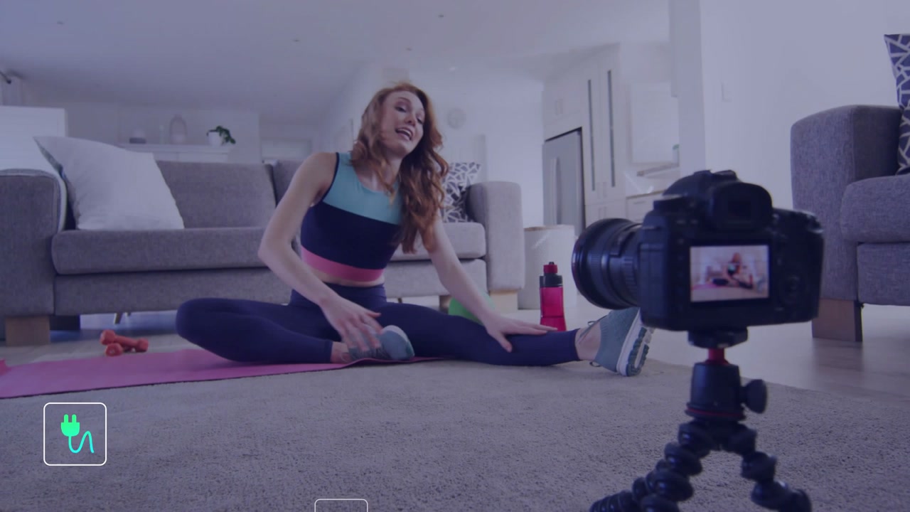 Fitness coach speaking to camera and doing seated stretches on yoga mat, talk activating help icons