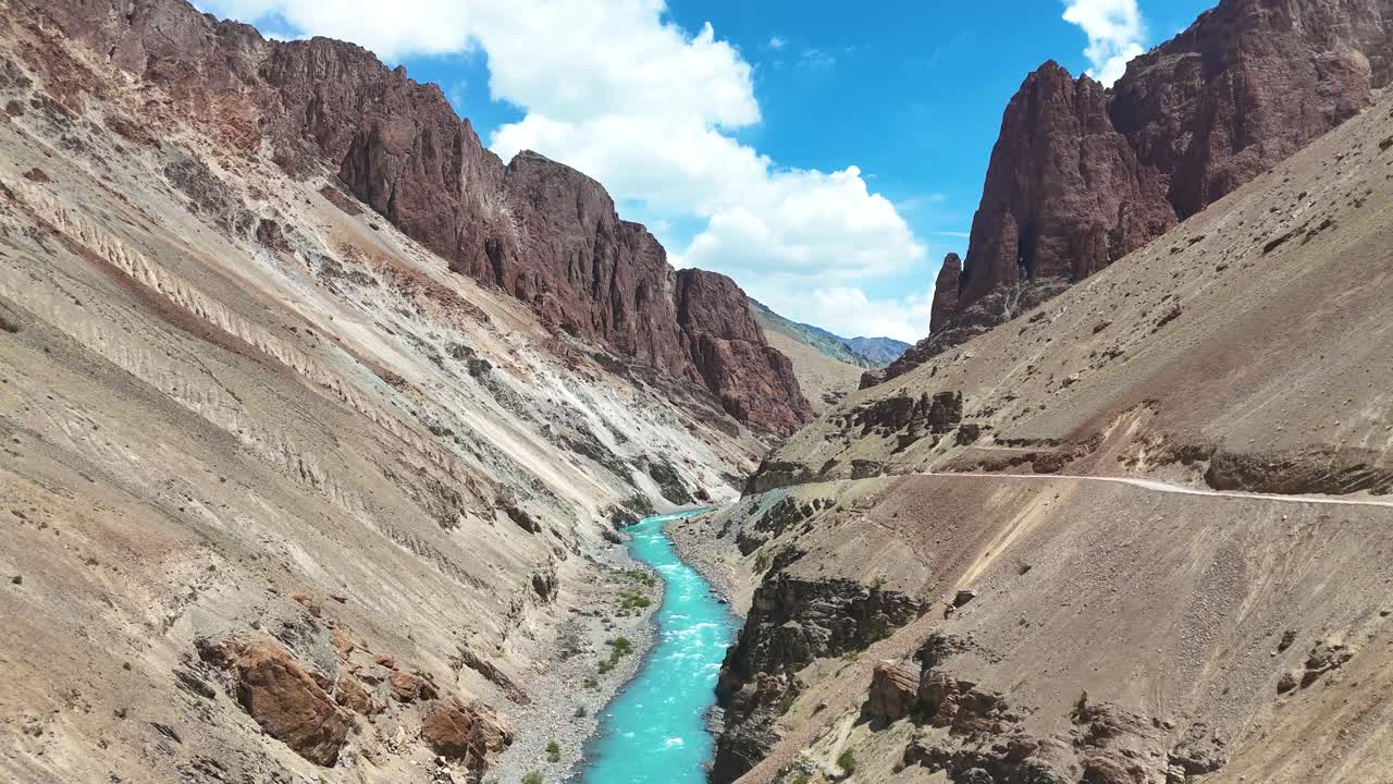 Aerial drone shot of a vibrant blue river flowing beside a secluded mountain monastery.