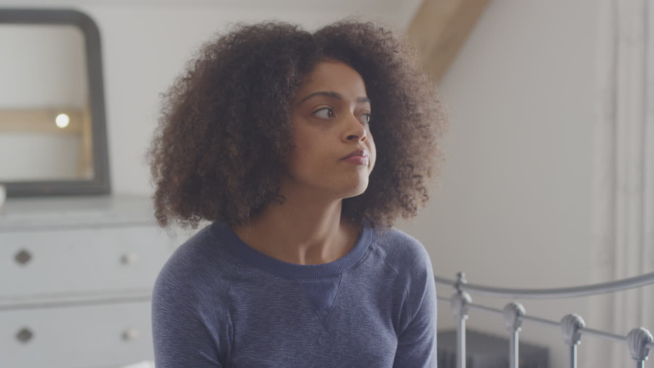 разочарованная женщина сидит на кровати в спальне дома с отрицательным домашним тестом на беременность