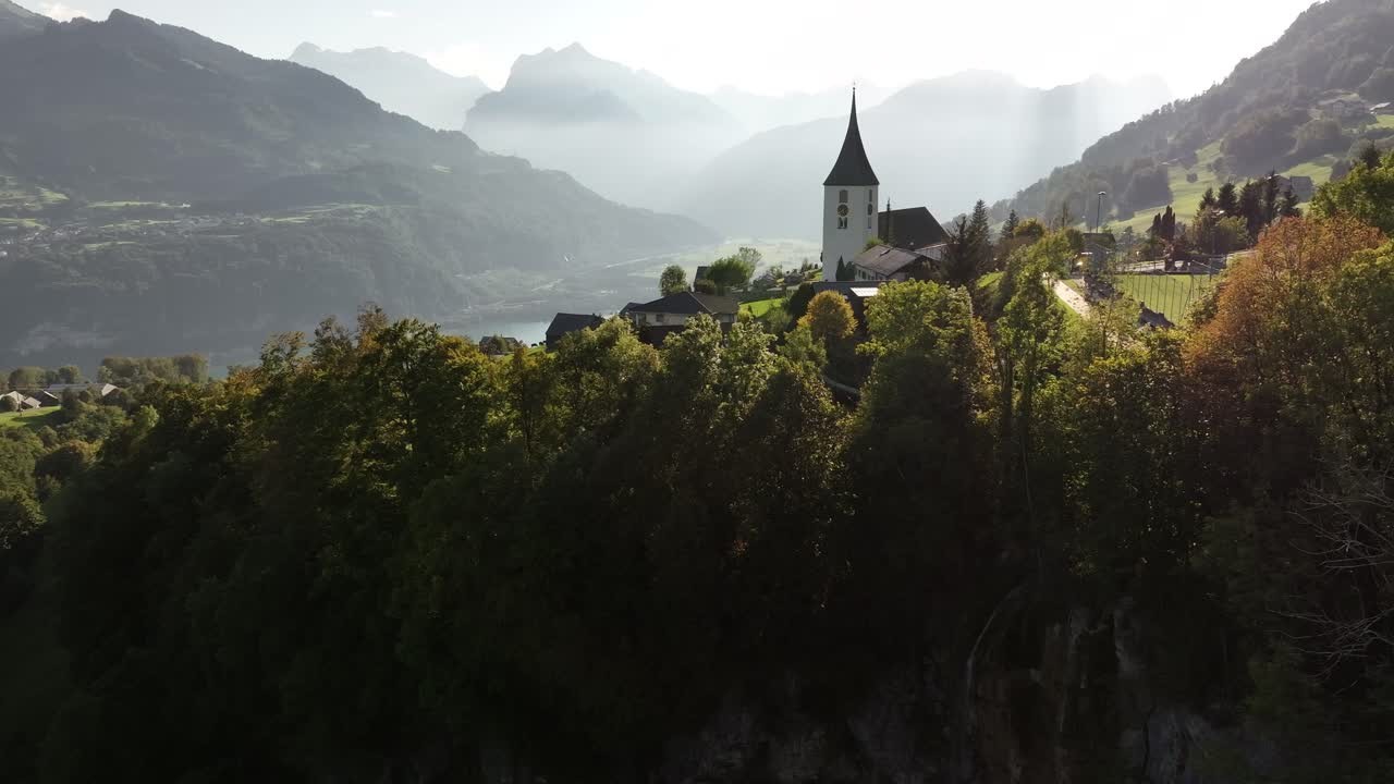 The Gallus church Amden overlooking the valley with the lake between the mountains. Morning rays shine on a favorite place in the alpine mountains