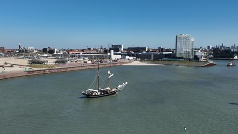 Sailing-Boat-at-The-Port-of-Scheveningen,-Netherlands,-Sunny-Day,-Aerial-Wide-Circling-Shot