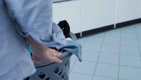 Woman-carrying-clothes-in-basket-trolley-at-laundromat-4k