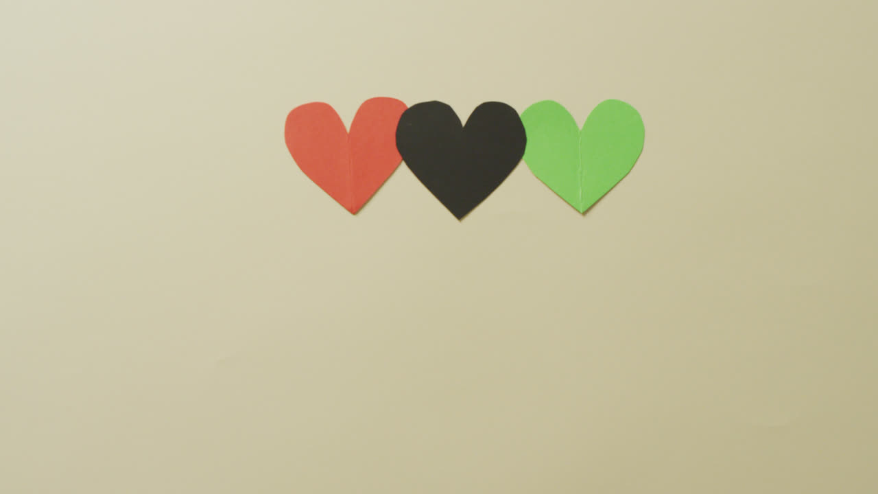video de corazones de papel rojo, negro y verde sobre fondo beige