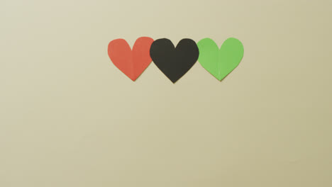 Video-of-red,-black-and-green-paper-hearts-on-beige-background