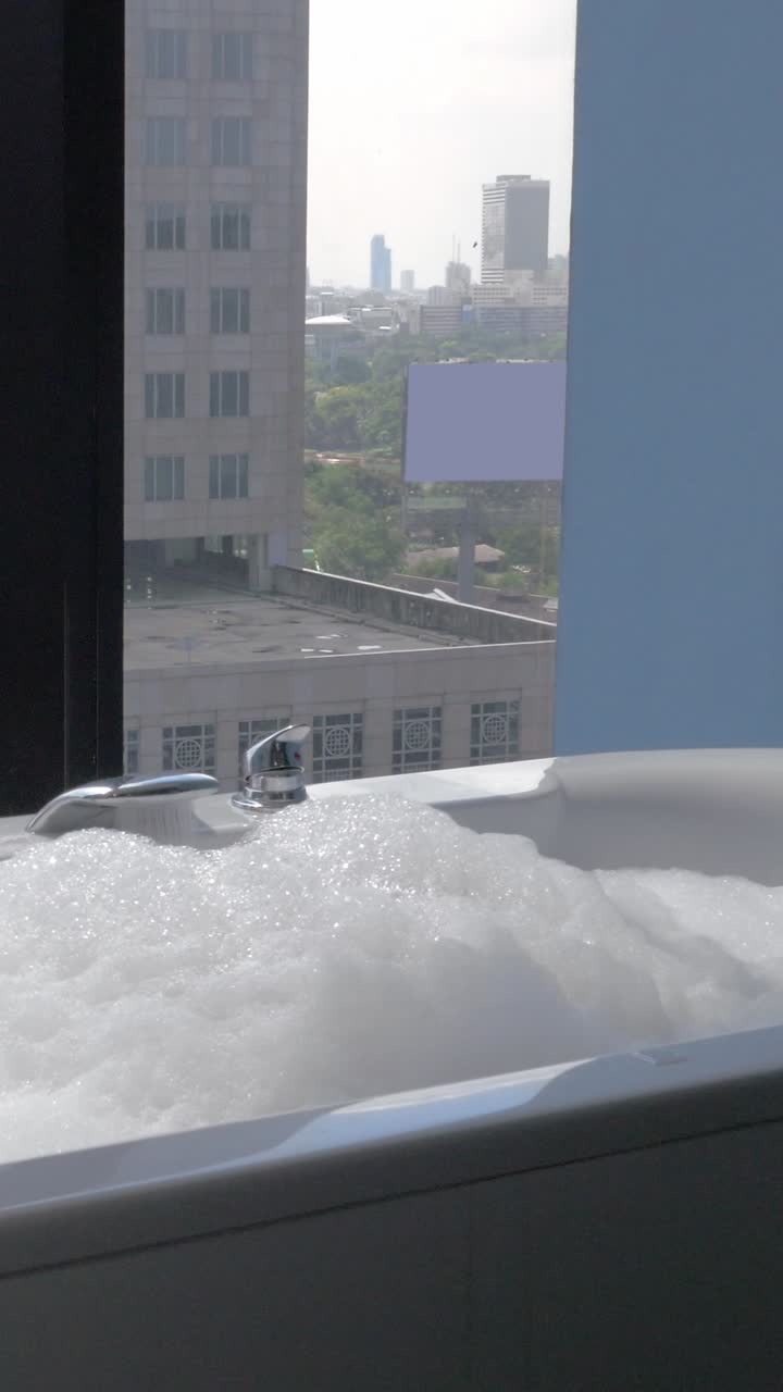 Vasca da bagno con bolle e vista sulla città da una finestra di un grattacielo